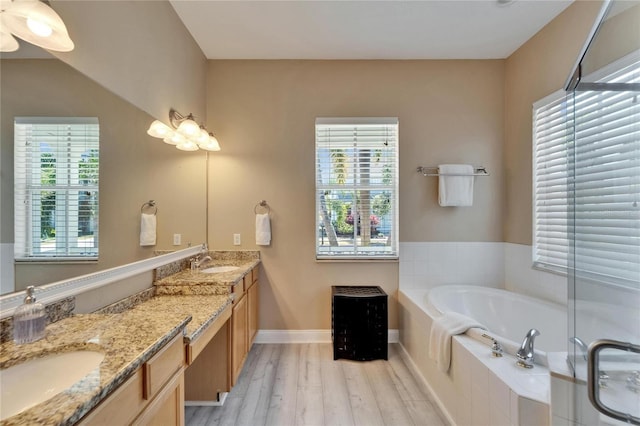 full bathroom featuring a sink, a bath, double vanity, and wood finished floors