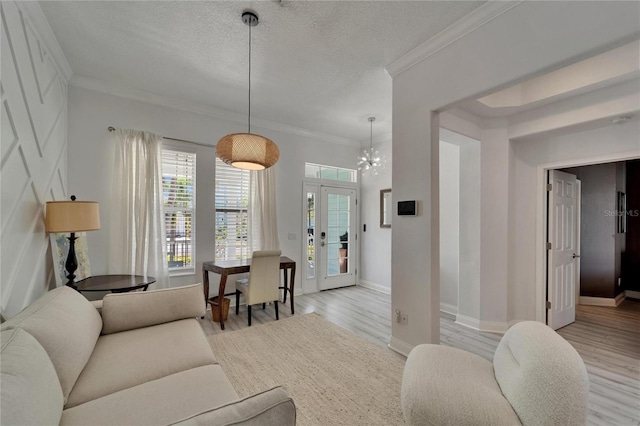 living room featuring crown molding, a wealth of natural light, light wood finished floors, and a textured ceiling
