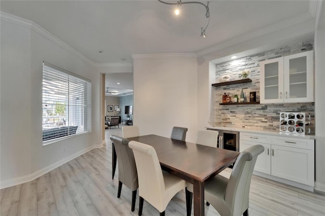dining space with light wood-style flooring, a dry bar, baseboards, and ornamental molding