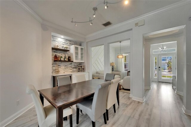 dining area with visible vents, baseboards, an inviting chandelier, ornamental molding, and light wood-style flooring