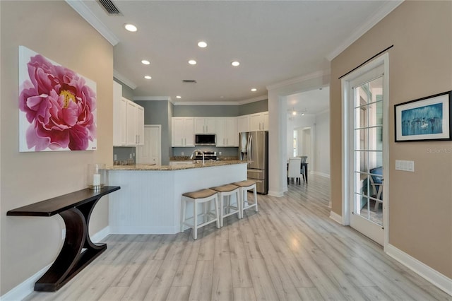 kitchen with ornamental molding, a peninsula, recessed lighting, light stone countertops, and stainless steel appliances