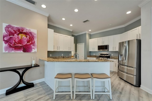 kitchen featuring stone countertops, a peninsula, light wood-style flooring, and appliances with stainless steel finishes