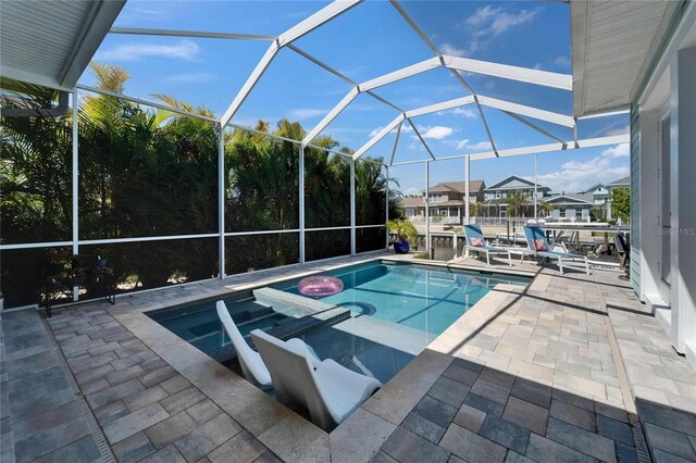 view of swimming pool featuring a patio area, a pool with connected hot tub, and glass enclosure