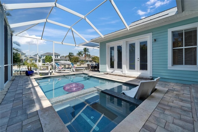 view of swimming pool featuring french doors, a pool with connected hot tub, a patio, and a lanai