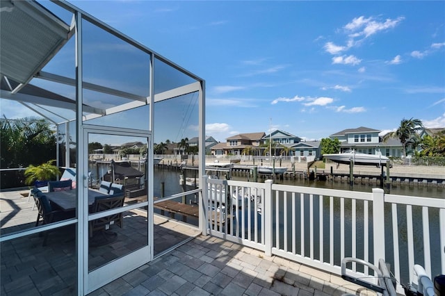 view of patio with a water view, a residential view, a lanai, and a dock