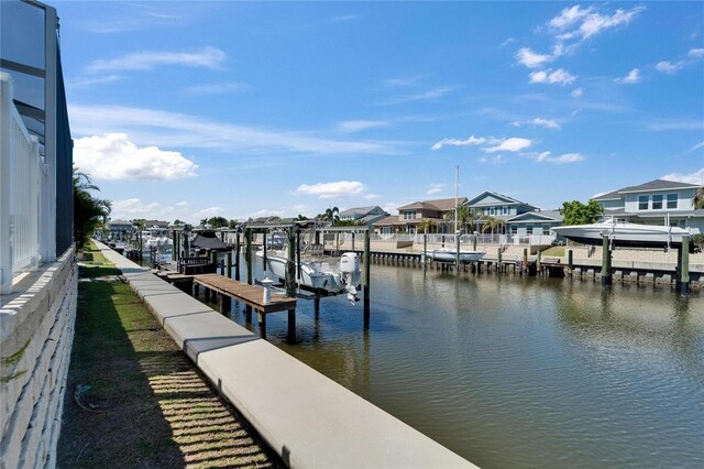 view of dock with boat lift, a residential view, and a water view