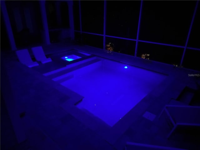 pool at night featuring an in ground hot tub
