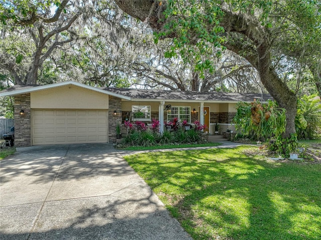 single story home featuring driveway, stone siding, covered porch, a front yard, and a garage