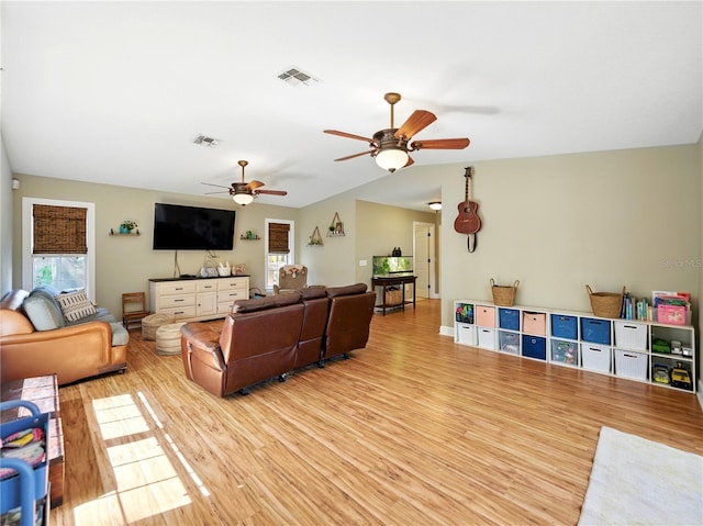 living area with wood finished floors, visible vents, vaulted ceiling, and ceiling fan