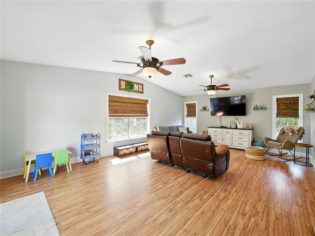 living room with vaulted ceiling, light wood-type flooring, ceiling fan, baseboards, and visible vents