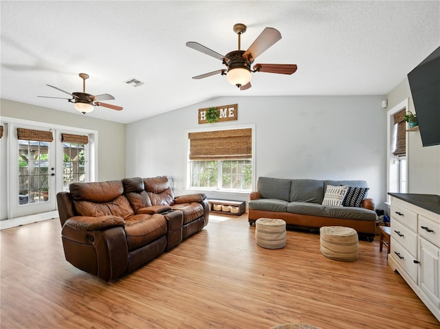 living room featuring lofted ceiling, visible vents, french doors, light wood-type flooring, and ceiling fan