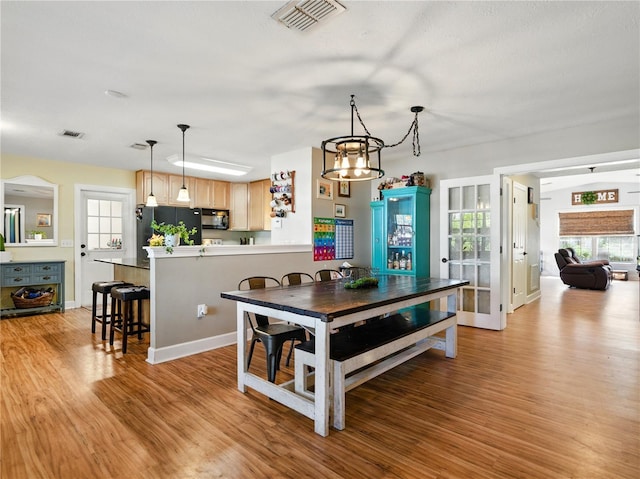 dining room with visible vents, light wood finished floors, and an inviting chandelier