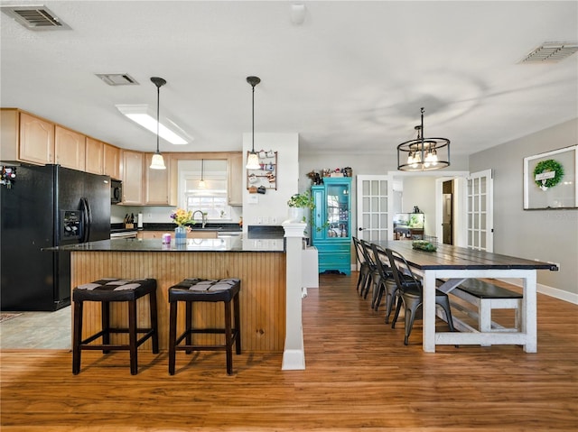 kitchen featuring visible vents, light wood finished floors, and black appliances