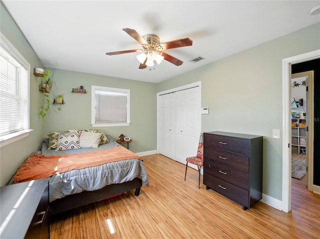 bedroom featuring light wood-style flooring, baseboards, visible vents, a closet, and ceiling fan