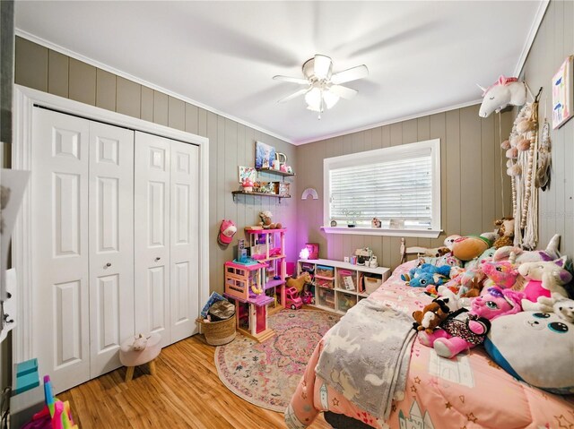 bedroom with wood finished floors, a closet, ceiling fan, and crown molding