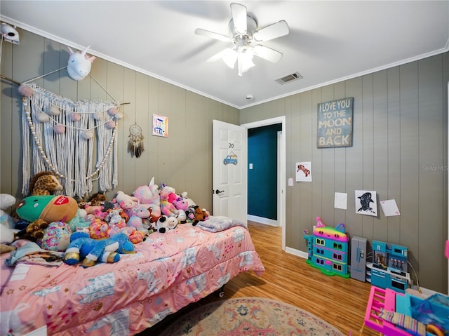 bedroom featuring baseboards, visible vents, a ceiling fan, wood finished floors, and crown molding