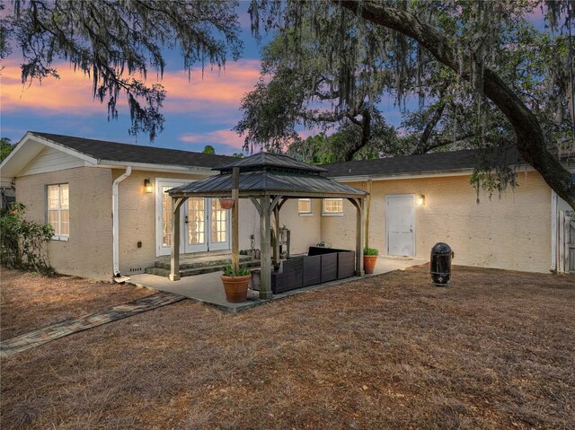 rear view of property with stucco siding, a gazebo, and a patio area