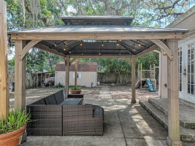 view of patio featuring fence, a shed, an outdoor structure, a carport, and a gazebo