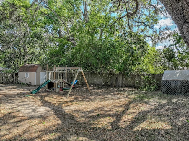 view of yard featuring a fenced backyard, an outdoor structure, a shed, and a playground