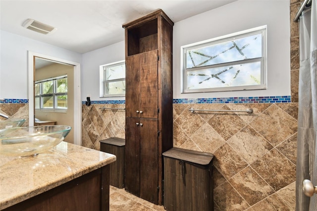 422 Dunedin Cir, Temple Terrace, FL 33617 - bathroom with visible vents, tile walls, wainscoting, a tile shower, and vanity