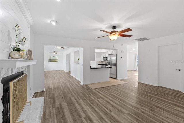 15118 Brushwood Dr, Tampa, FL 33624 - unfurnished living room featuring a ceiling fan, light wood-style flooring, a high end fireplace, and baseboards