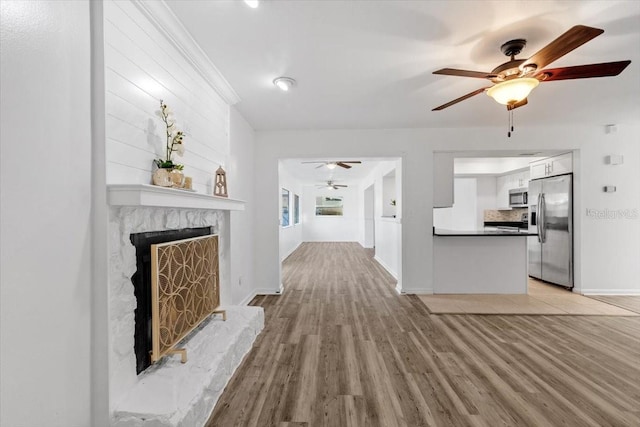 15118 Brushwood Dr, Tampa, FL 33624 - unfurnished living room with ceiling fan, light wood-style floors, a premium fireplace, and baseboards