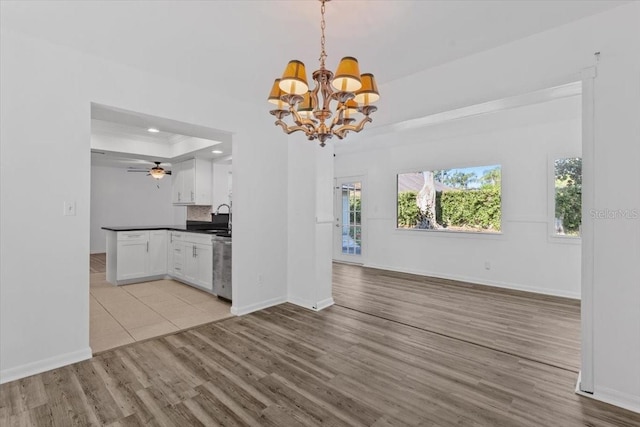 15118 Brushwood Dr, Tampa, FL 33624 - kitchen featuring open floor plan, a chandelier, a tray ceiling, light wood-style floors, and crown molding