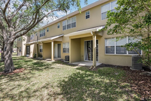 rear view of property with stucco siding, central AC, and a lawn