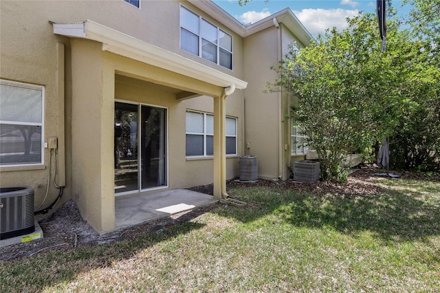 back of property featuring stucco siding, a yard, central AC, and a patio