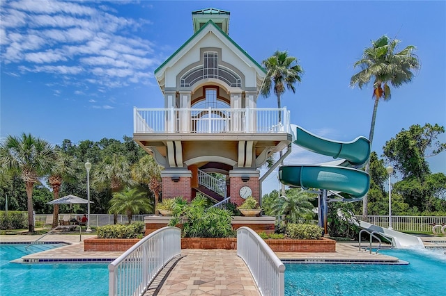 community pool with fence, a patio area, and a water slide