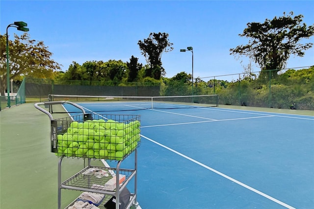 view of tennis court featuring fence and community basketball court