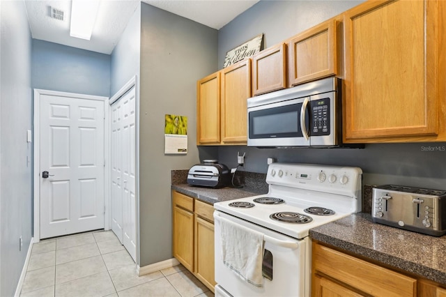 kitchen featuring stainless steel microwave, white electric range oven, baseboards, and dark countertops