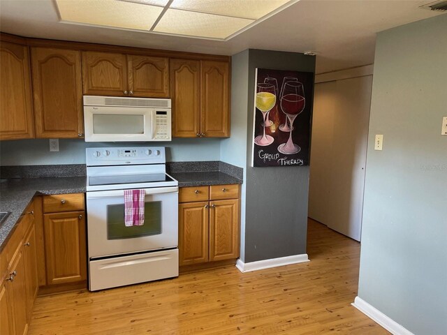 825 S Village Dr N Unit 201, Saint Petersburg, FL 33716 - kitchen with white appliances, light wood finished floors, baseboards, and brown cabinets