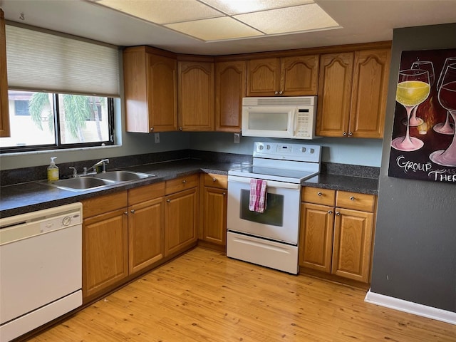 825 S Village Dr N Unit 201, Saint Petersburg, FL 33716 - kitchen featuring white appliances, a sink, brown cabinetry, light wood finished floors, and dark countertops