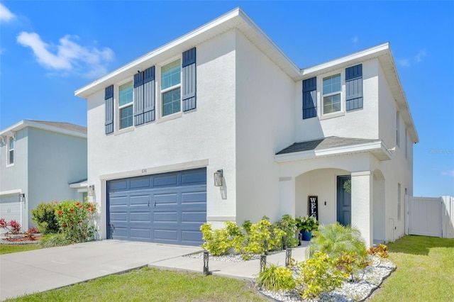view of front of property with an attached garage, driveway, fence, and stucco siding