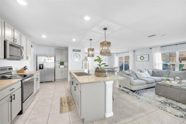 kitchen with light tile patterned floors, open floor plan, a sink, and appliances with stainless steel finishes