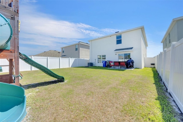 view of yard with central AC, a fenced backyard, and a playground