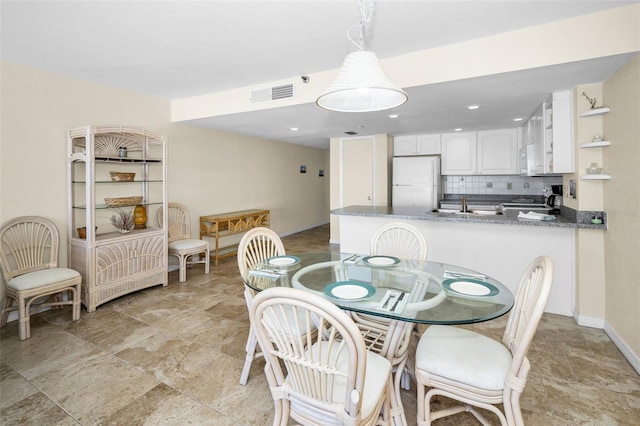 dining space featuring baseboards, visible vents, and stone finish floor