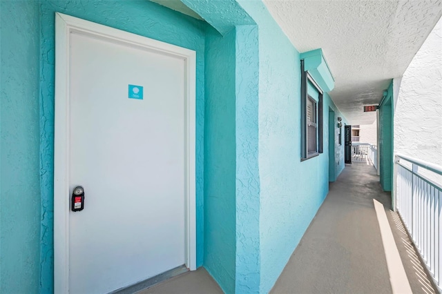 view of exterior entry featuring a balcony and stucco siding
