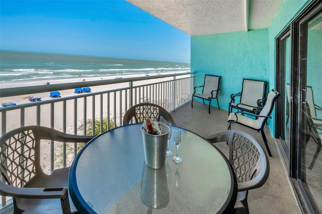 balcony featuring a view of the beach, a water view, and outdoor dining space