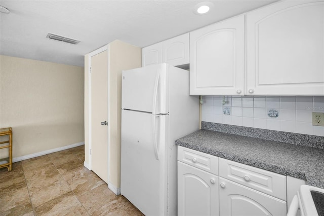 kitchen featuring dark countertops, tasteful backsplash, white cabinets, visible vents, and freestanding refrigerator