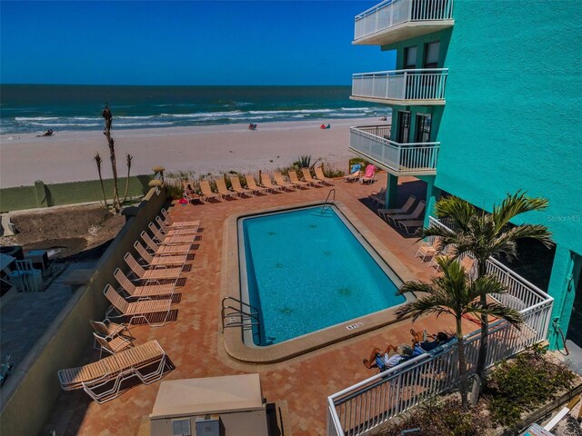 pool with a beach view, a water view, and a patio