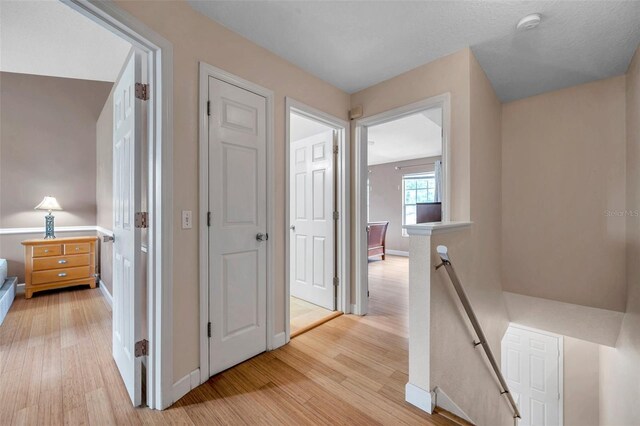 13777 Forest Lake Dr, Largo, FL 33771 - hallway featuring baseboards, light wood-style floors, and an upstairs landing