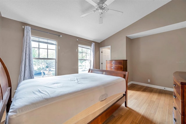 13777 Forest Lake Dr, Largo, FL 33771 - bedroom featuring a textured ceiling, light wood-type flooring, vaulted ceiling, baseboards, and a ceiling fan