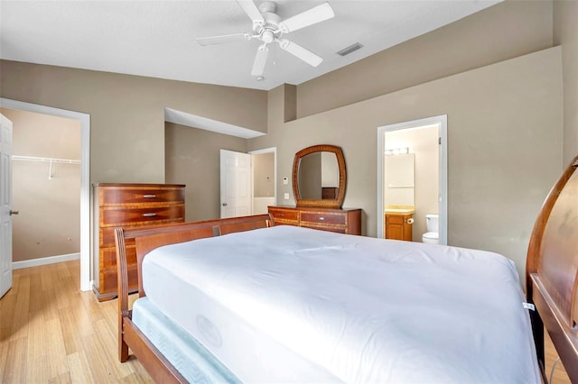 13777 Forest Lake Dr, Largo, FL 33771 - bedroom with vaulted ceiling, connected bathroom, a walk in closet, a closet, and light wood-style flooring