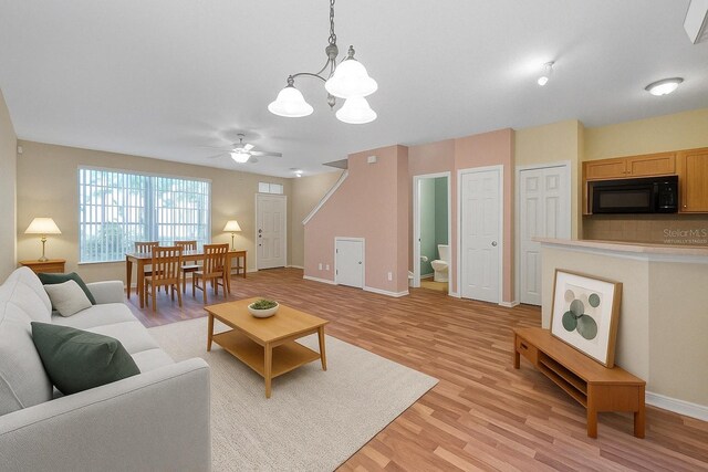 13777 Forest Lake Dr, Largo, FL 33771 - living room featuring light wood finished floors, baseboards, and ceiling fan with notable chandelier