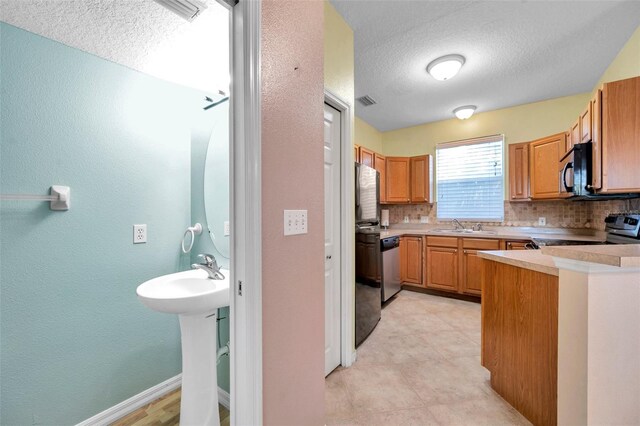 13777 Forest Lake Dr, Largo, FL 33771 - kitchen featuring a textured wall, a textured ceiling, appliances with stainless steel finishes, and a sink