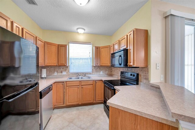 13777 Forest Lake Dr, Largo, FL 33771 - kitchen featuring a sink, a textured ceiling, tasteful backsplash, light countertops, and black appliances
