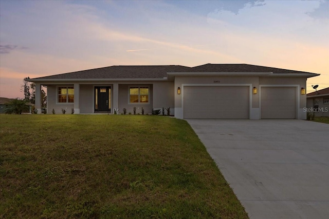 10493 Grail Ave, Englewood, FL 34224 - prairie-style house featuring a garage, driveway, stucco siding, and a front lawn