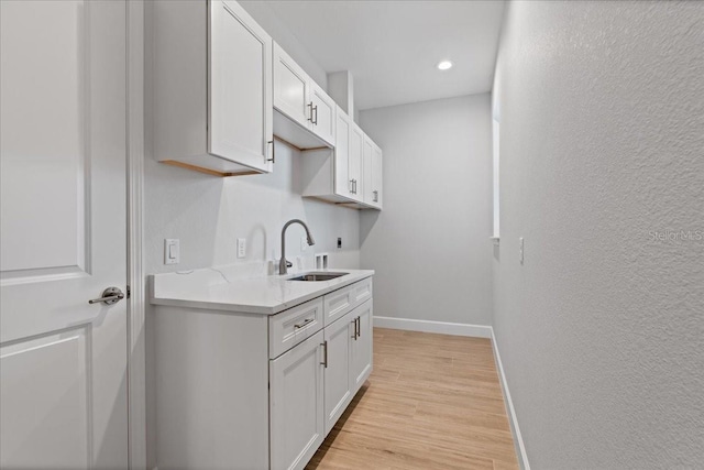 10493 Grail Ave, Englewood, FL 34224 - kitchen featuring light wood-style floors, a textured wall, a sink, and baseboards